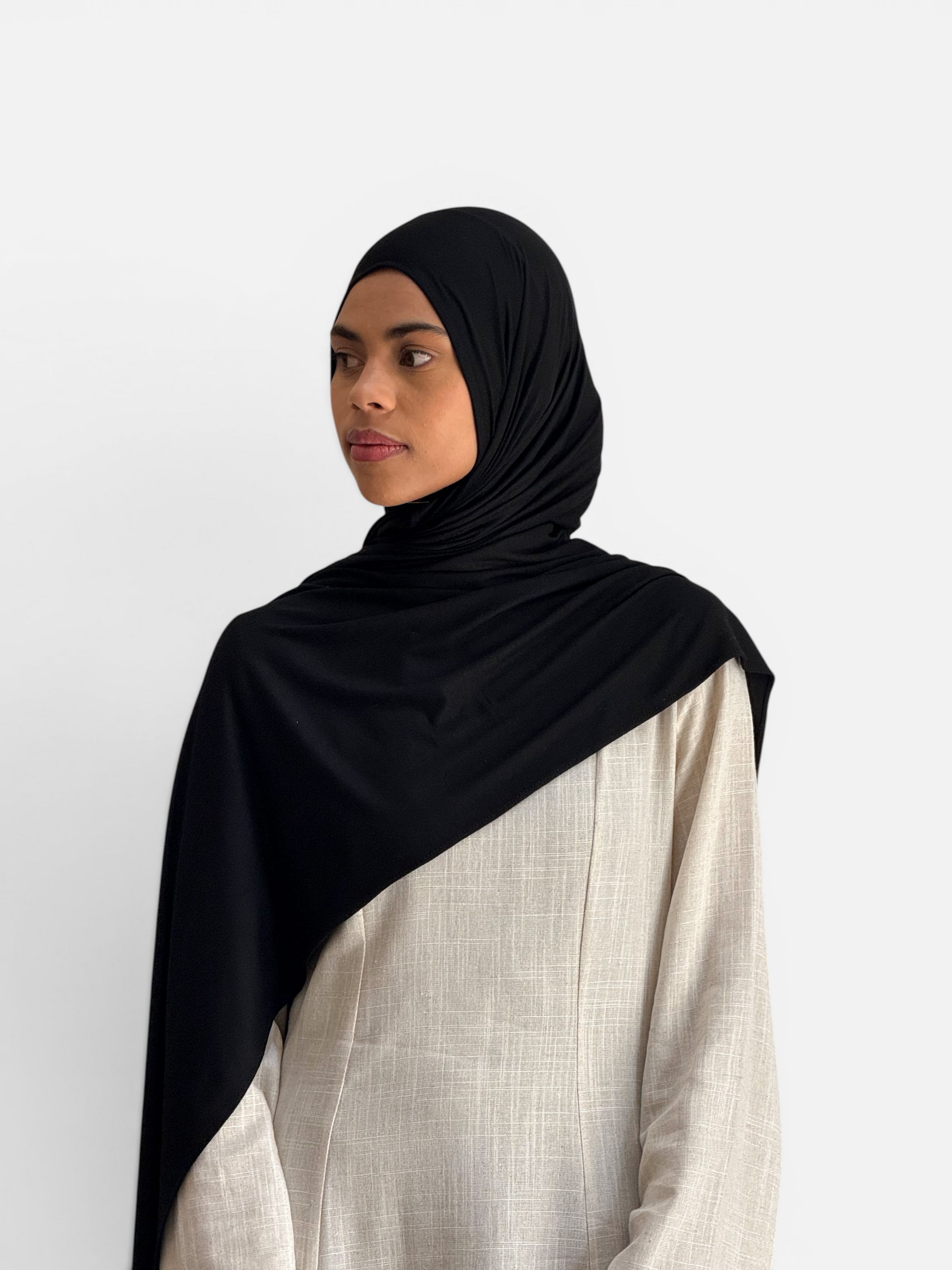 Model wearing a SAHR STUDIOS black premium cotton jersey hijab scarf with a soft sheen and comfortable stretch
