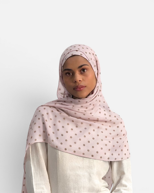 Model wearing a SAHR STUDIOS light pink modal hijab with brown polka dot pattern against a white background